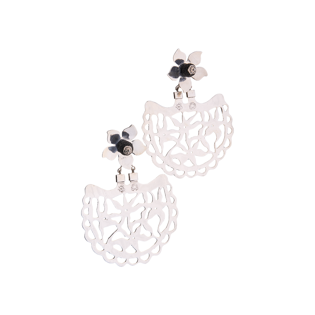Two silver earrings with a flower at the top. The flower has a volcanic black stone in the center. Below the flower is an open fan shaped piece with an intricate design.