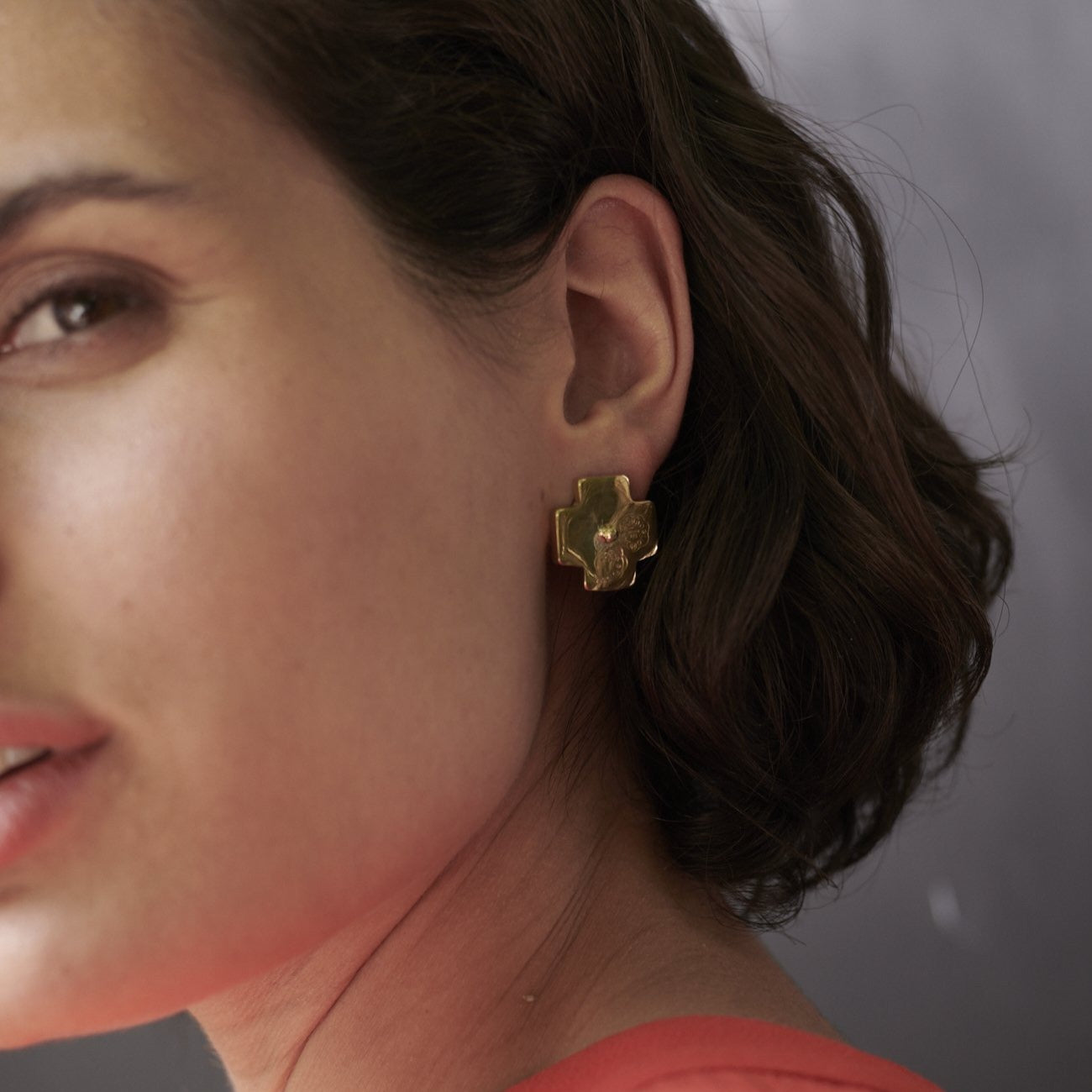 woman using golden earring with a cross shape