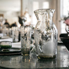 A glass and a pitcher on top of a table.