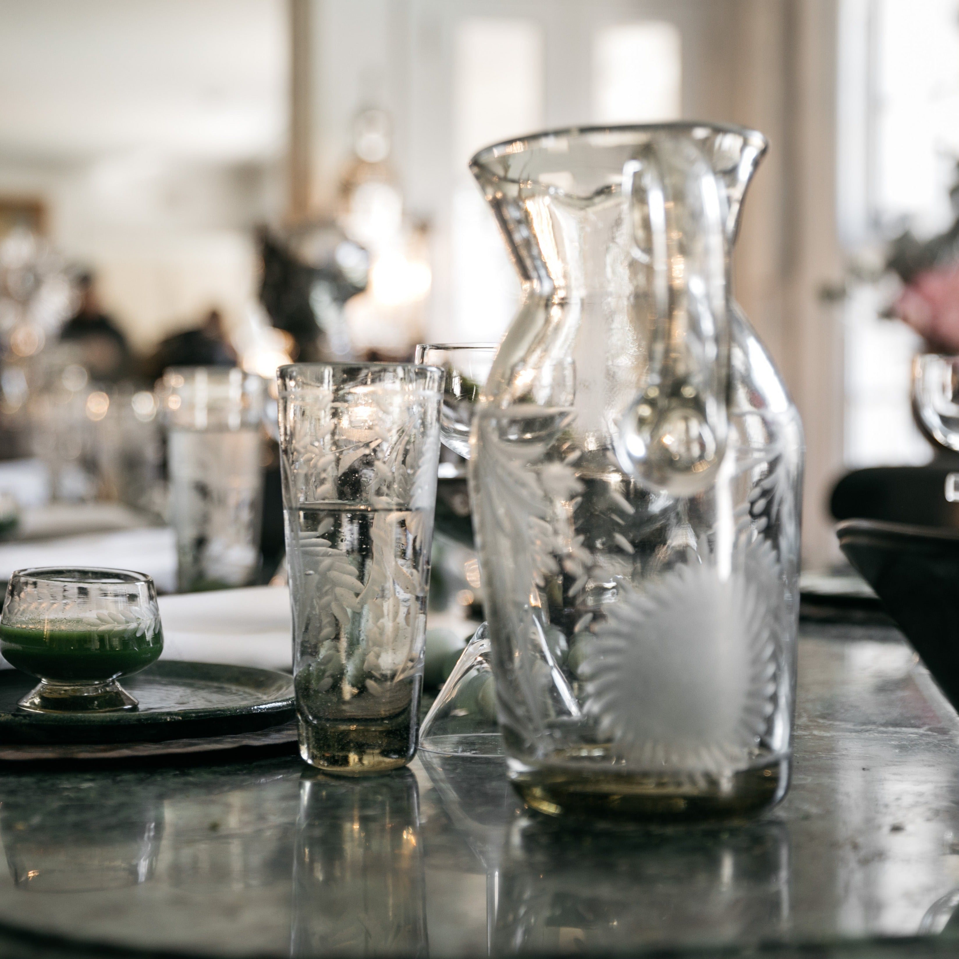 A glass and a pitcher on top of a table.