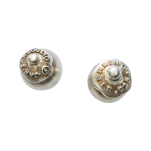 Two silver studs earrings with a signature seal. Plain background.