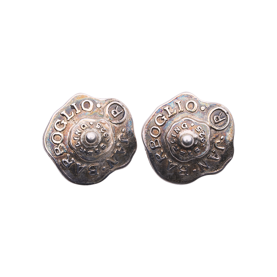 Old silver wavy circle earrings with  the name of the designer and where they were made. In the center is a silver bead.