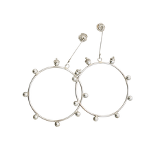 Silver hoops with decorative balls with seals around the hoop. Holding the hoop is a silver stick with the designer's seal.