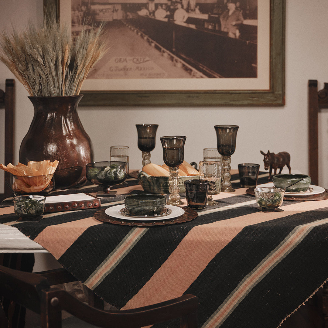 A table set with plates and dark glass cups.