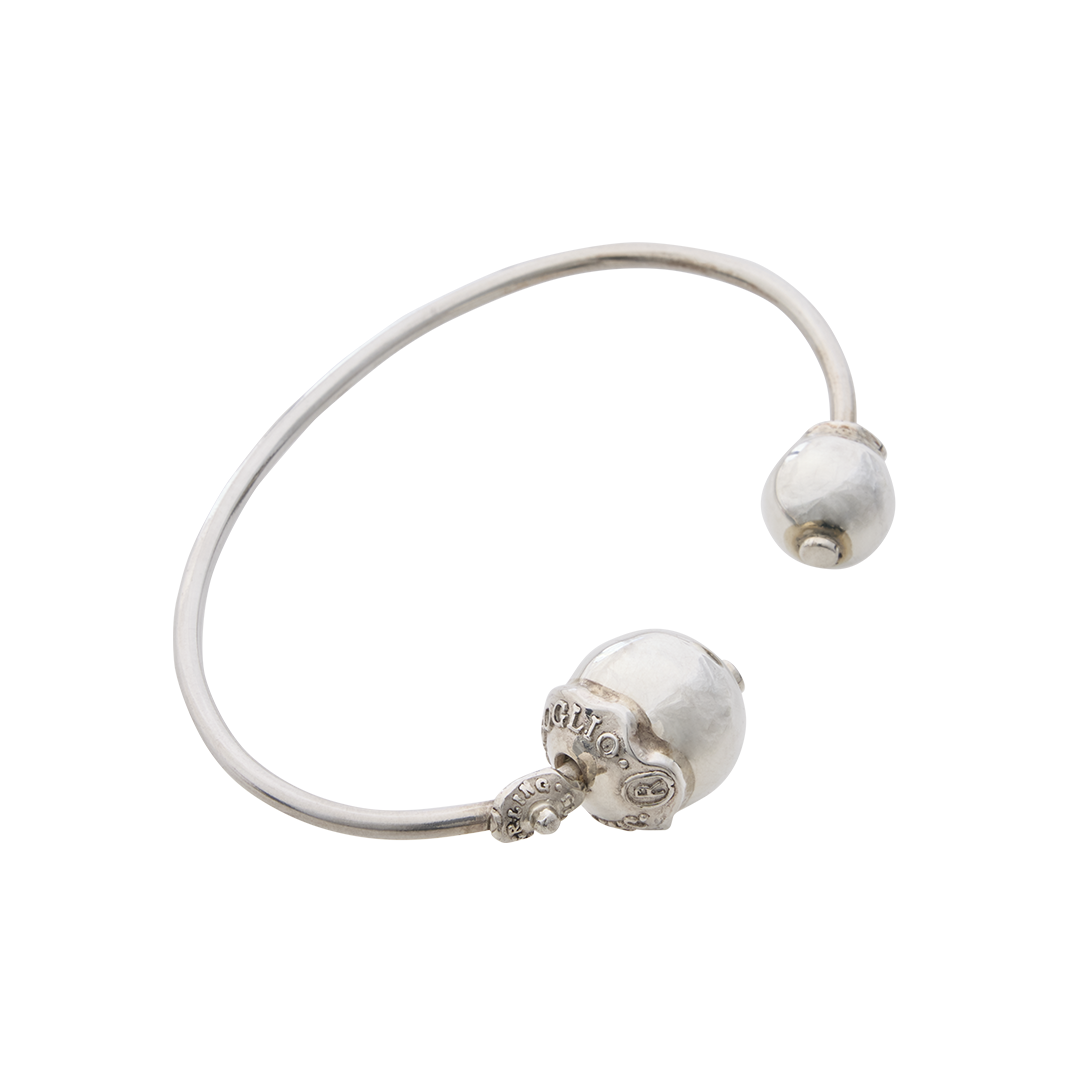 A silver thin bracelet with two silver studs, one in each end of the bracelet. One stud has two seals with the signature of the designer engraved and where the bracelet was made.