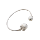 A silver thin bracelet with two silver studs, one in each end of the bracelet. One stud has two seals with the signature of the designer engraved and where the bracelet was made.