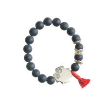 Black beads bracelet with a silver cross with two engraved seals and a red string charm.