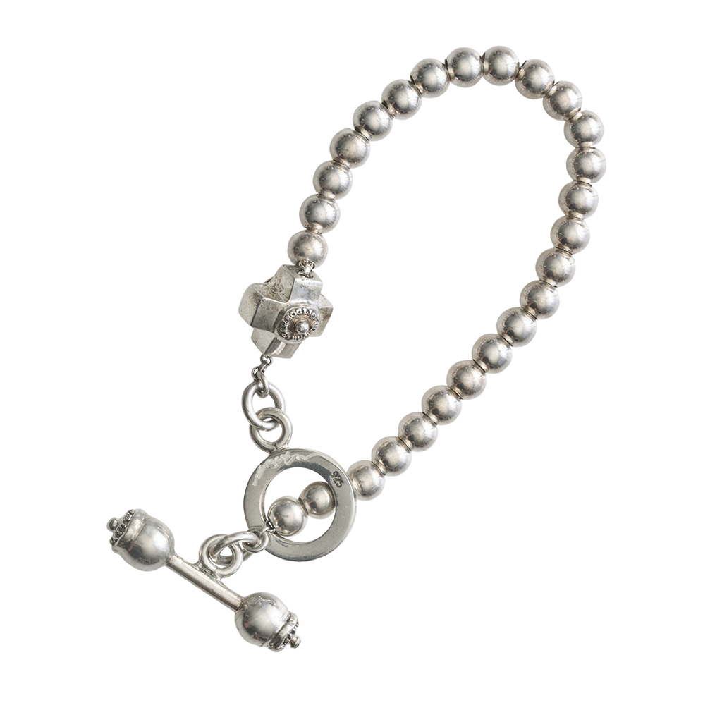 A silver beads bracelet with a cross. The closing mechanism is a stick wit tho balls with a seal passing trough a circle, where there is an engraved signature.