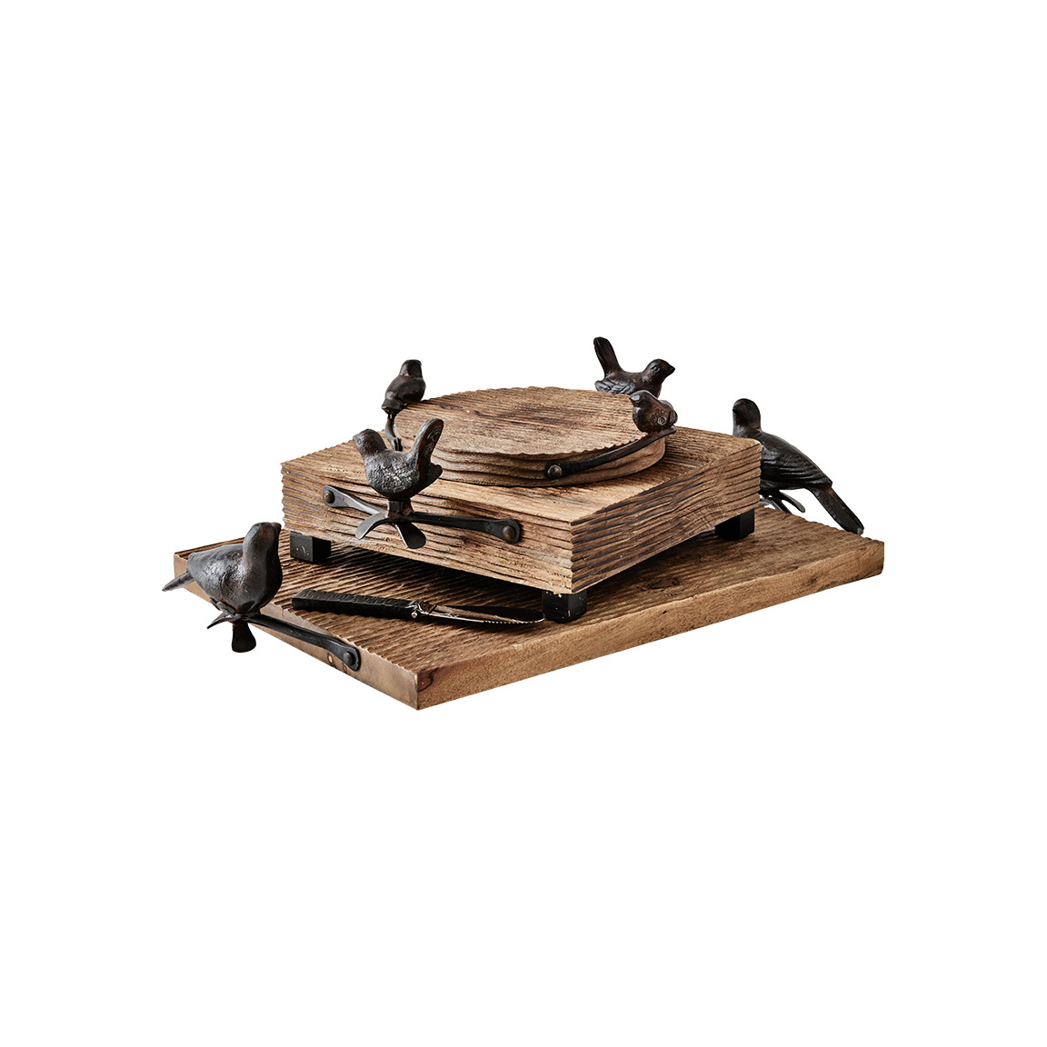 Three  wood cutting boards with cast iron bird handles stack on top of each other. The bottom one has a rectangle shape, the middle one a square shape and the one on the top a circle.