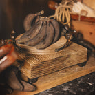 Several brown bananas on top of a wood cutting tray on top os another trays.