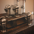 Several  mini angels plated in nickel with halo on a square base and four candles on top of a book and a wooden surface.