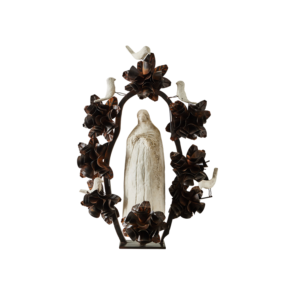 A hand carved stone statue representing the spirit of the virgin of  Guadalupe surrounded by an aura and halo of iron flowers and stone birds. 