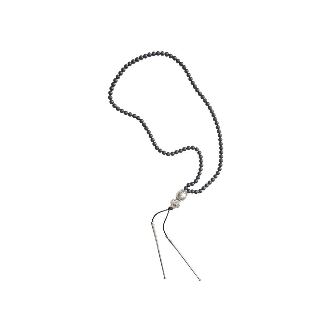 A necklace with black beads and at the end a silver ball and a silver cross followed by two black leather strings with two silver cylinders or topers. 
