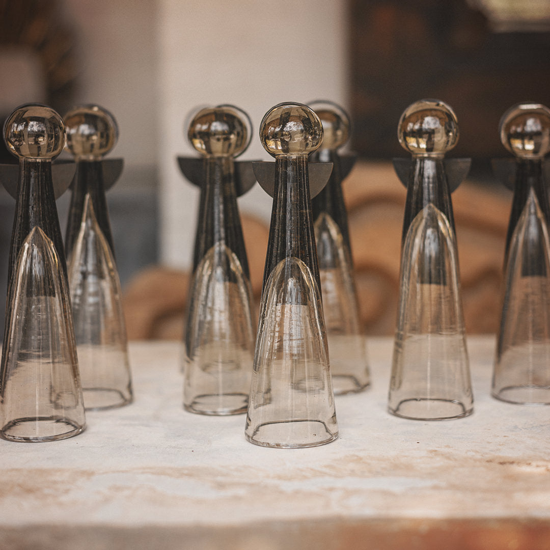 Several  mouth blown glass angels  with iron wings and halo standing next to each other  on top of a white surface.