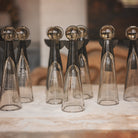 Several  mouth blown glass angels  with iron wings and halo standing next to each other  on top of a white surface.
