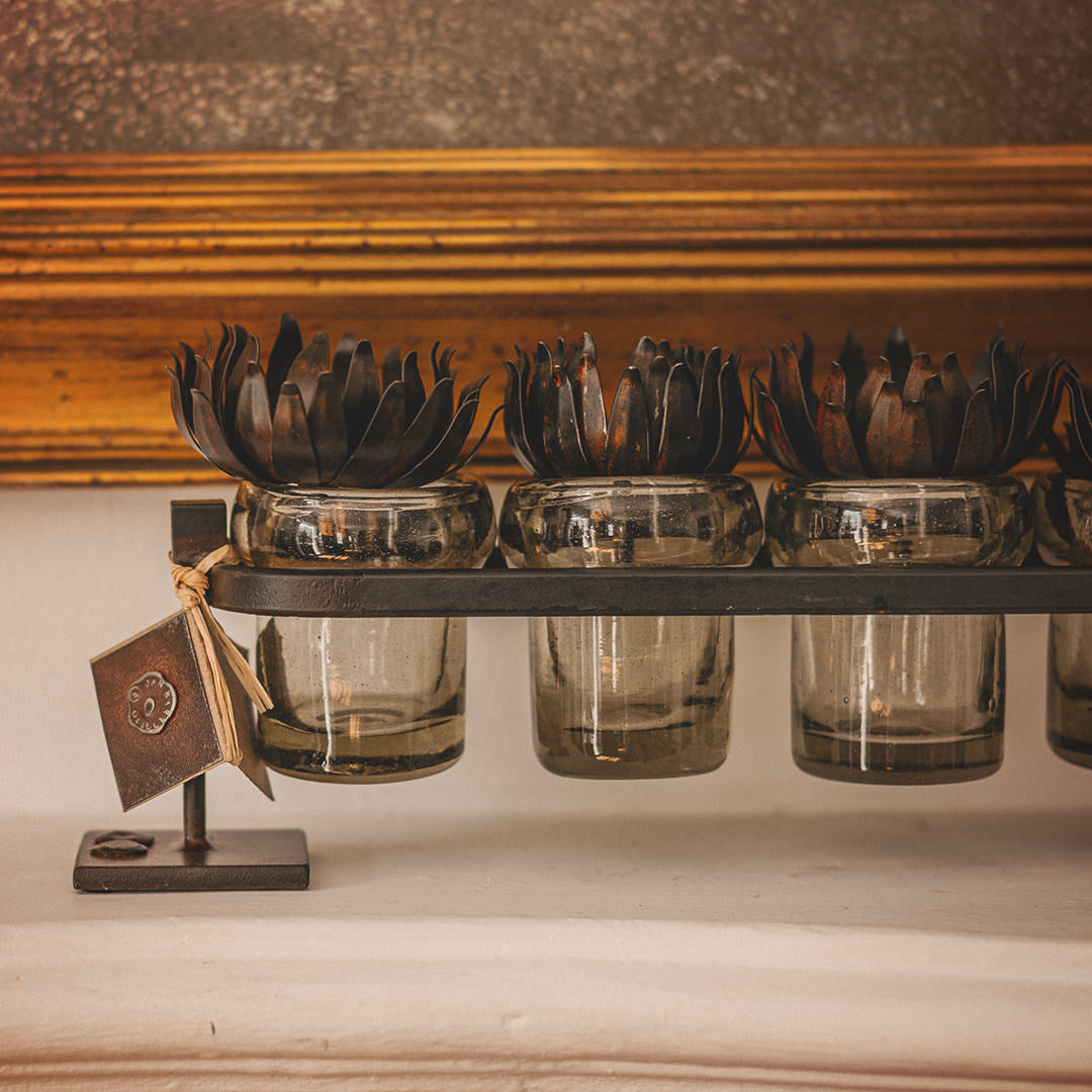 Wax cast railroad with mouth blown glass votive holders on a forged  iron stand.  Iron flowers on top of each glass.
