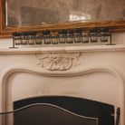 Wax cast railroad with mouth blown glass votive holders on a forged iron stand. Iron flowers on top of the glasses. On top of a white chimney.