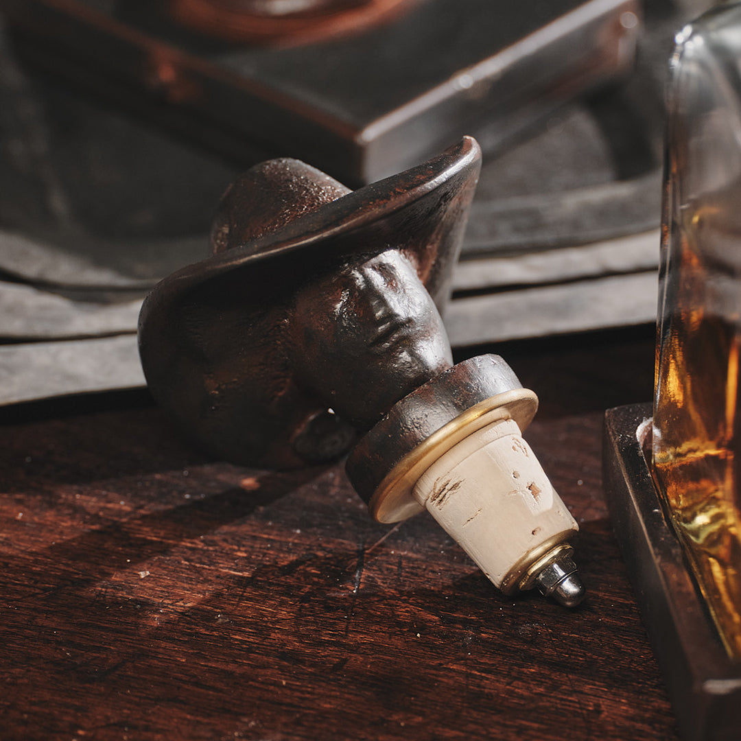 A iron topper with the shape of a cowboy's face on top of a wood surface.