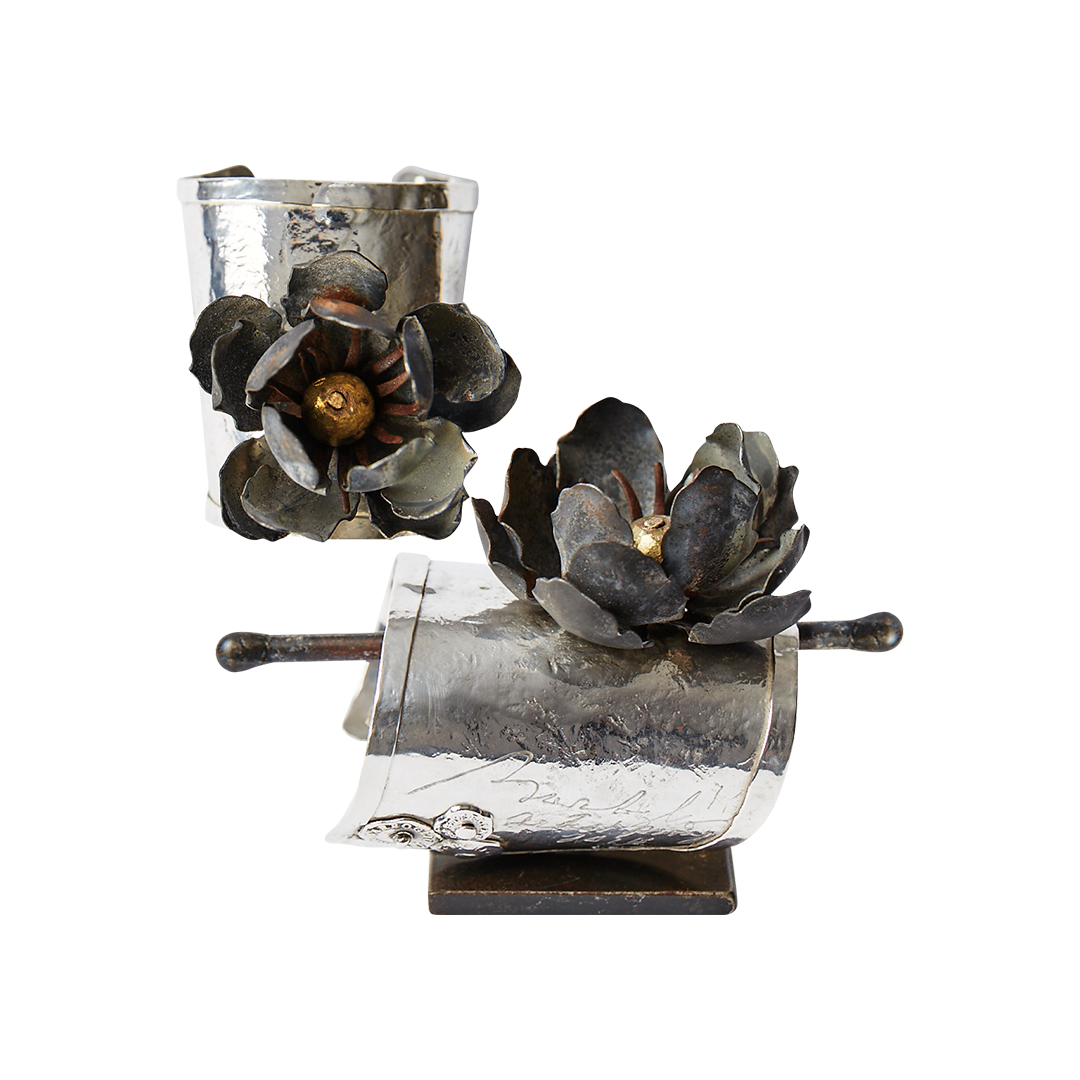 Two silver cuffs with a dark metal rose. One cuff shows the front view and the other shows the side view. 