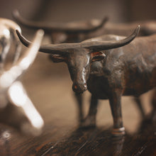 A close up to the head of a iron longhorn bull sculpture standing on a wood floor.