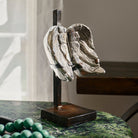 Heavy wax cast nickel wings on iron stand on top of a green table.