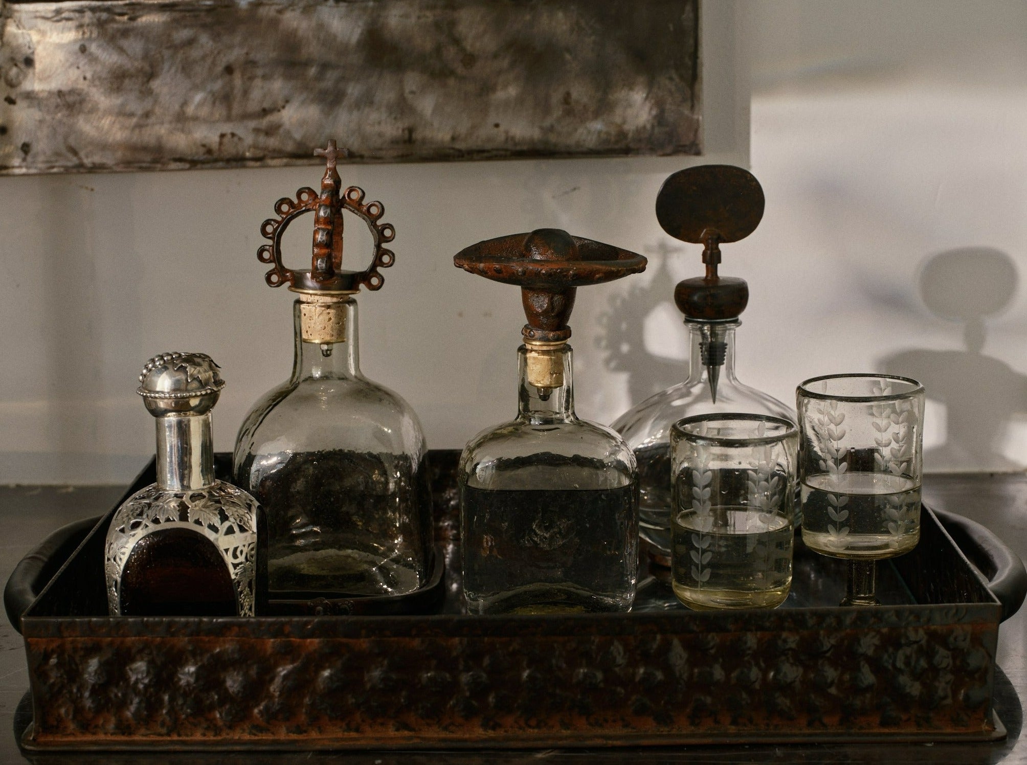 A hammered ottoman tray with four decanter and two glasses.