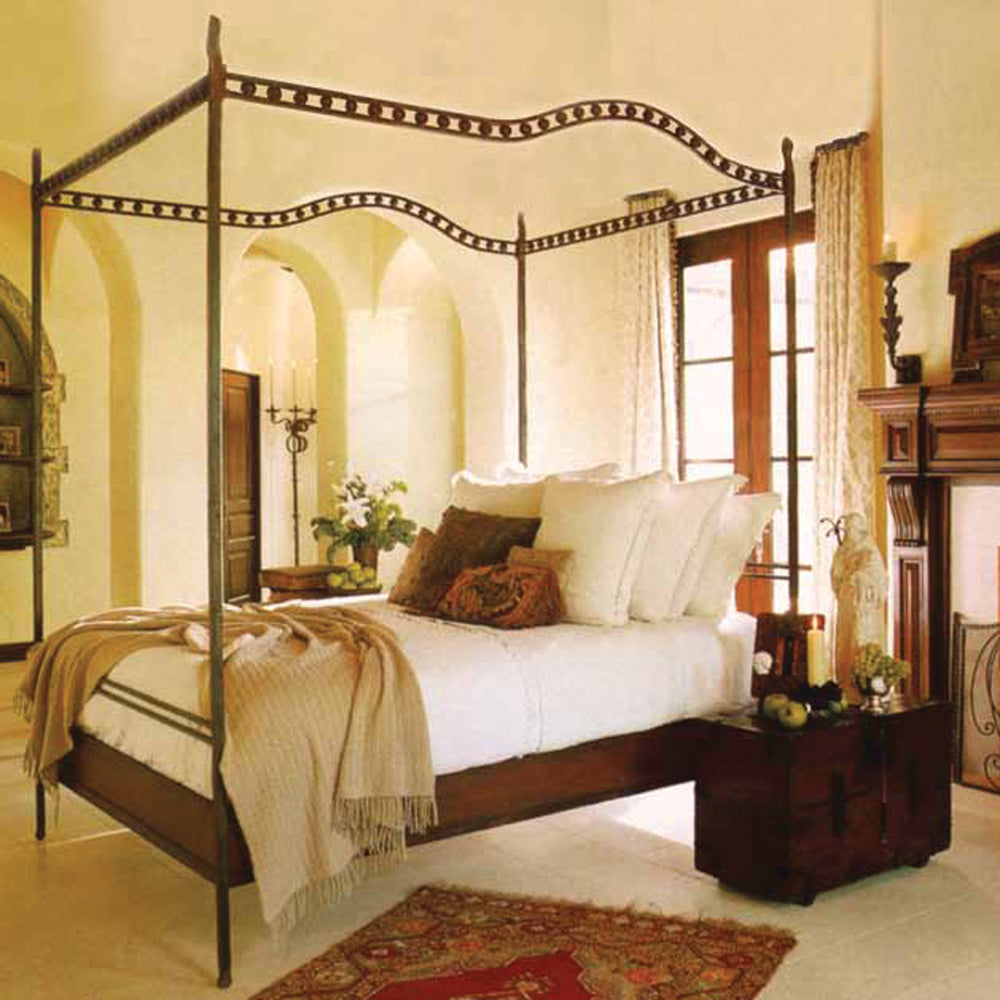 A canopy bed with white pillows and sheets- Inside a room with white walls and white floor.