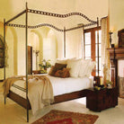 A canopy bed with white pillows and sheets- Inside a room with white walls and white floor.