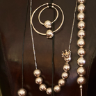 Several silver necklace with beads and hoops resting on a leather background.