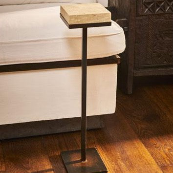 A hand carved stone top table with iron stand. In front of a white sofa.