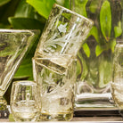 Two glasses stack on top of each other. Next to it a smaller glass. Green background.