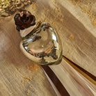 A mouth blown puffed glass heart with platinum finish and tiny iron rose on top of a fabric with ribbons and grains of rice.