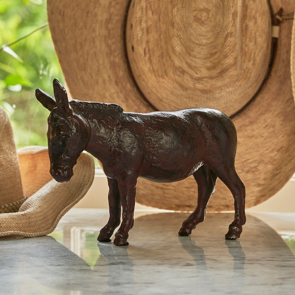 An iron donkey. Behind t is a light brown hat.  Outside background.