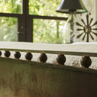 A iron wall with iron balls on top. On the background is a lamp and a window.