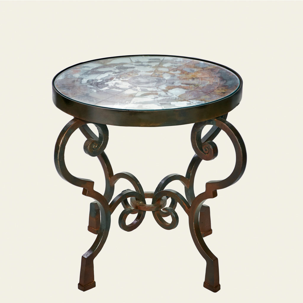 A round  table with antique mirror mosaic top on forged iron base. White background.