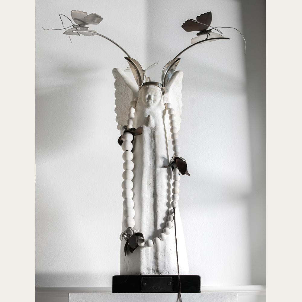 A white stone angel with nickel butterfly crown and white blessing beads with flowers. White bacckground.