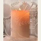 A lit candle inside a glass with engravings.