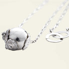 A silver bead with three seals and a delicate silver chain behind. A simple background.