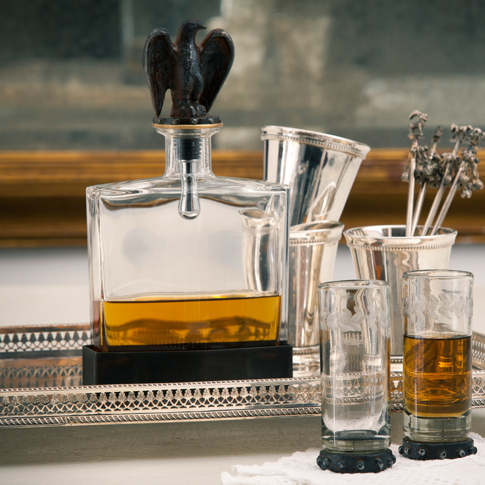Clear glass decanter with dual purpose cork & screw, eagle topper and iron stand. Some glasses and a tray. 