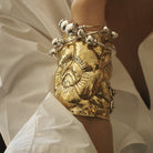 A wrist with a golden cuff and silver bracelets.