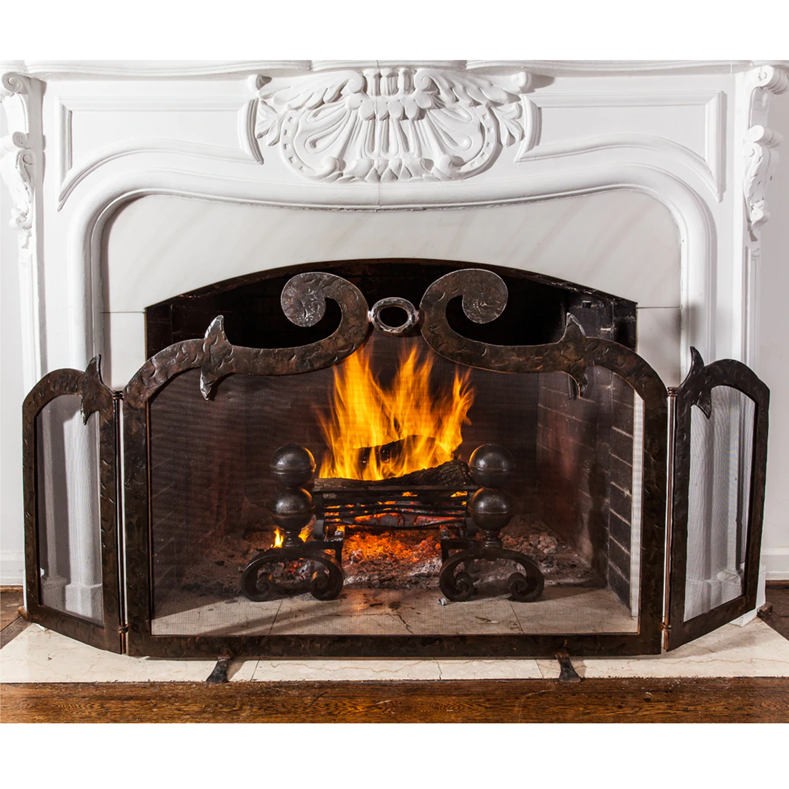 A hand forged fire screen with heavy iron frame. In front of a lit white chimney.
