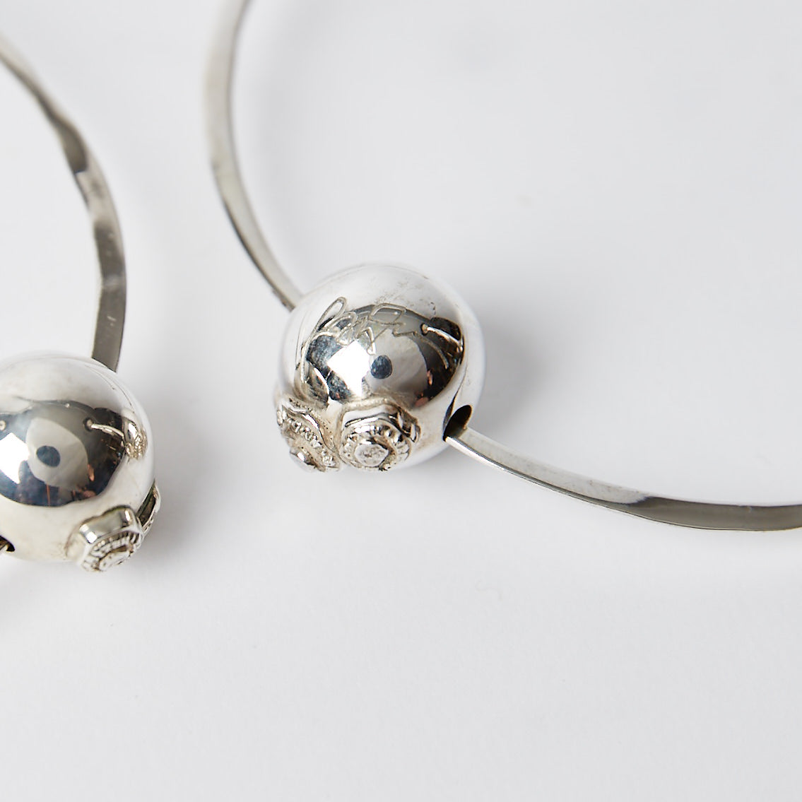 A silver bead with two seals and engraved with a signature. 