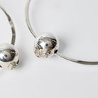 A silver bead with two seals and engraved with a signature. 