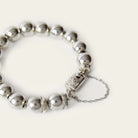 A silver bead bracelet with a rectangle and a delicate chain. Plain background.