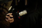 Hands of a woman clasp toguether. The woman is wearing black attire and silver cuffs with black beads bracelets.