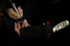 An older woman's hand engraving a silver bracelet.