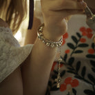 A children's wrist  with a silver bracelet with a cross charm.