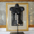 A black manikin of a woman's torso with two silver necklaces.