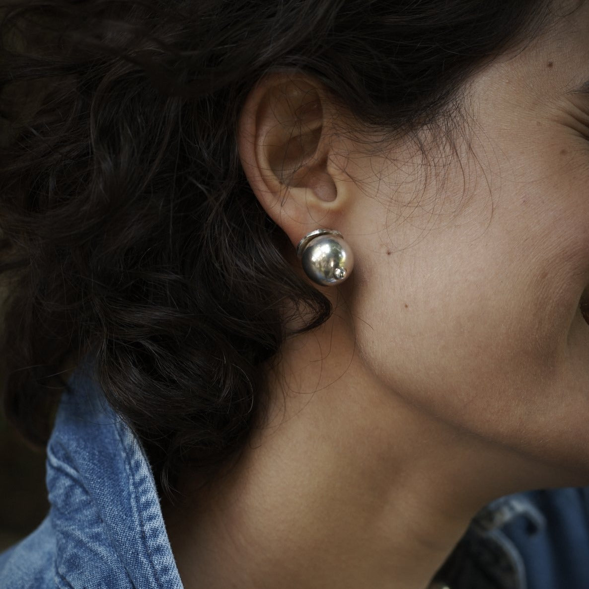 A woman's ear with a silver stud earring.