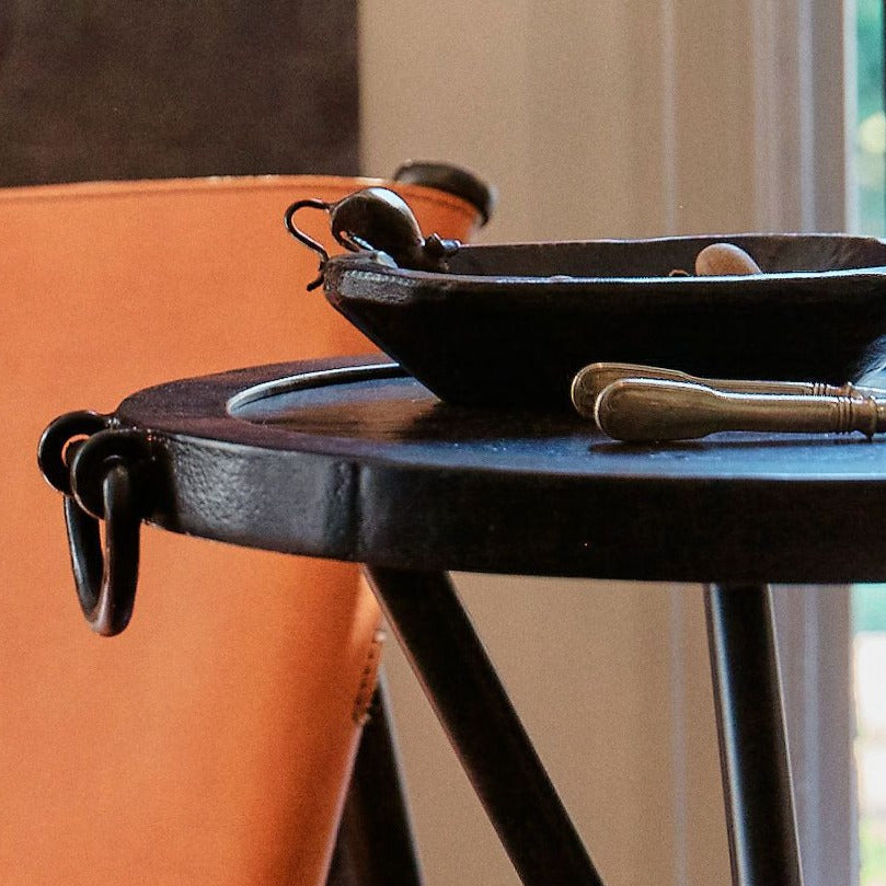 A  iron tabletop with heady d-ring handles . On top is a dark bowl with an iron mouse. 